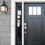 black front door with gray house siding nad porch lantern on with doorbell and silver handle
