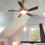 dark brown wood ceiling fan with light in a vaulted ceiling with a window and bed down below 