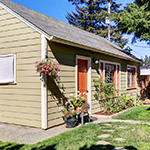 small beige guest house with red doors and grass